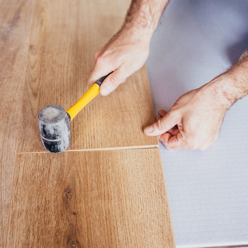 Person Hammering Wooden Plank Flooring Into Place